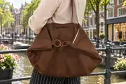 Eine Frau schiebt ihr historisches Fahrrad über die Plaza von Tazacorte auf La Palma und trägt dabei die Ledertasche Sarah zip M (Art. 25102)