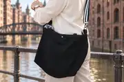 Eine Frau schiebt ihr historisches Fahrrad über die Plaza von Tazacorte auf La Palma und trägt dabei die Ledertasche Sarah zip M (Art. 25102)